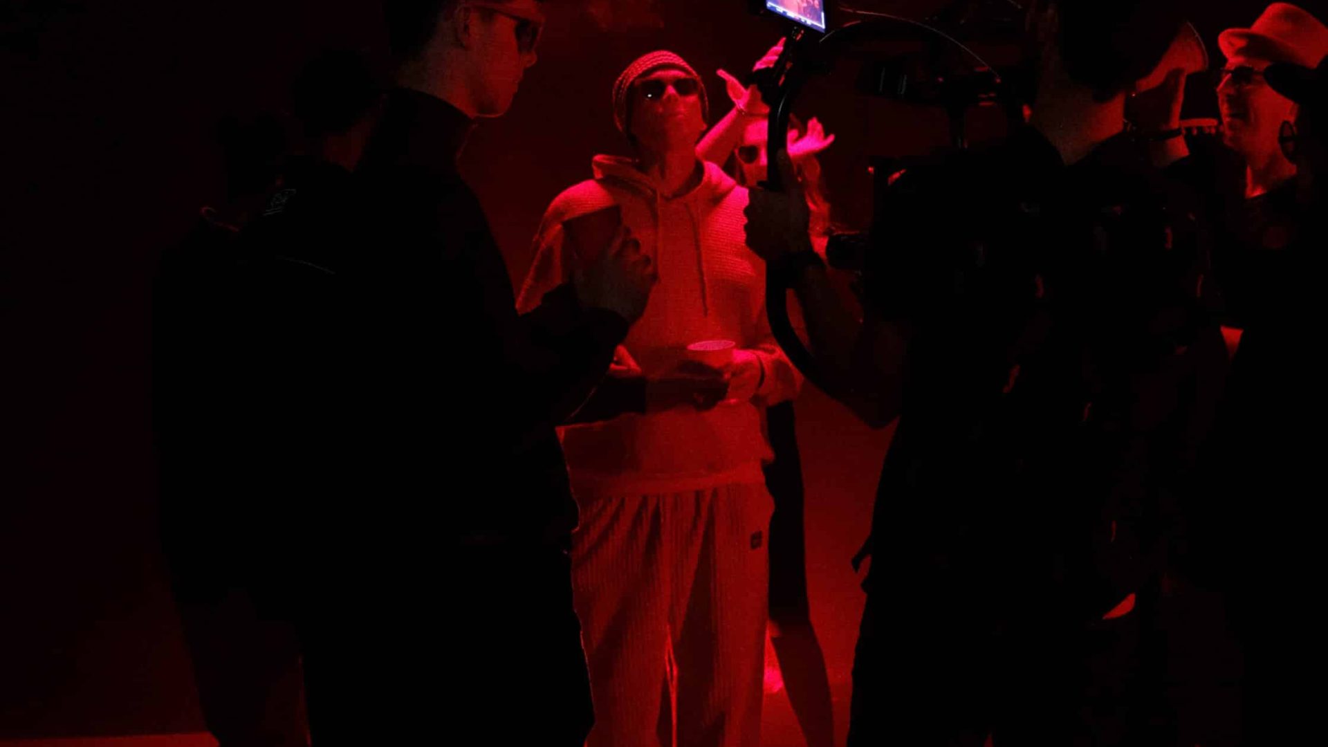 Filmmakers working on a video shoot in a dark, red-lit studio environment.