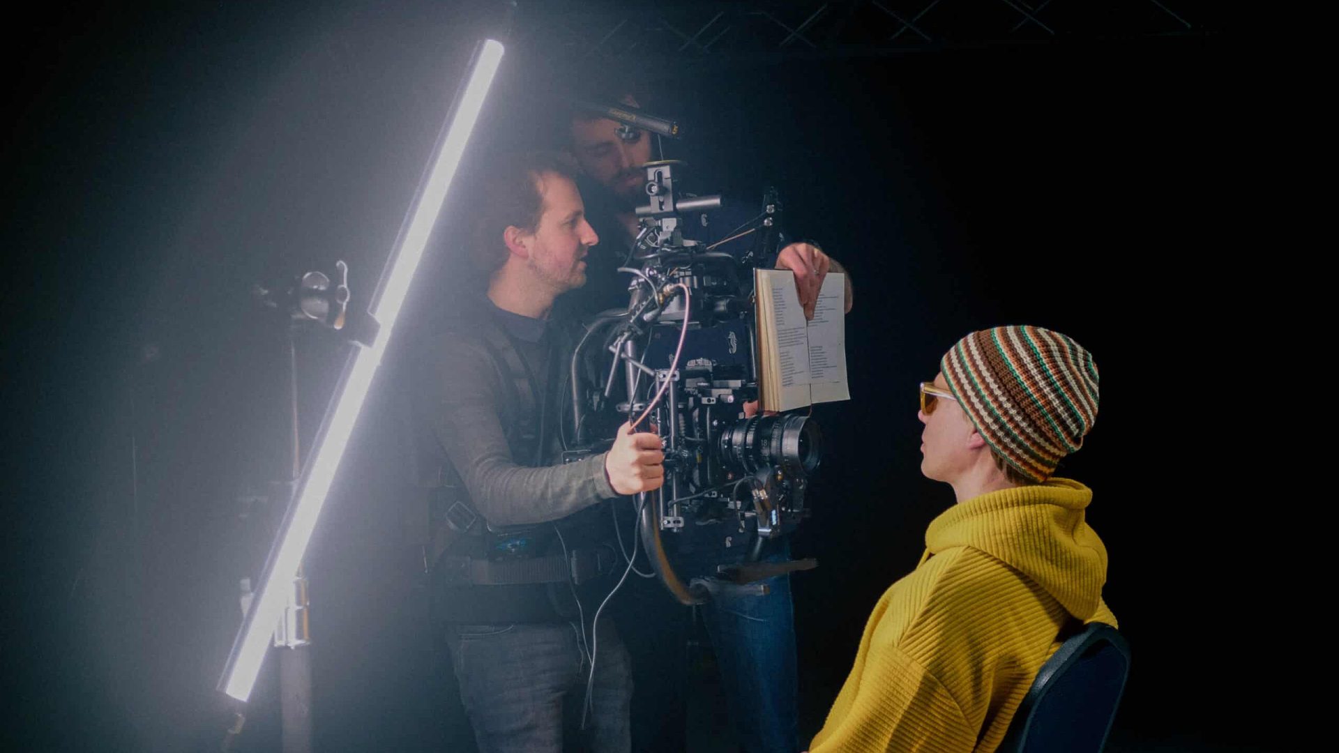 Filmmakers filming a client in a professional studio setting.