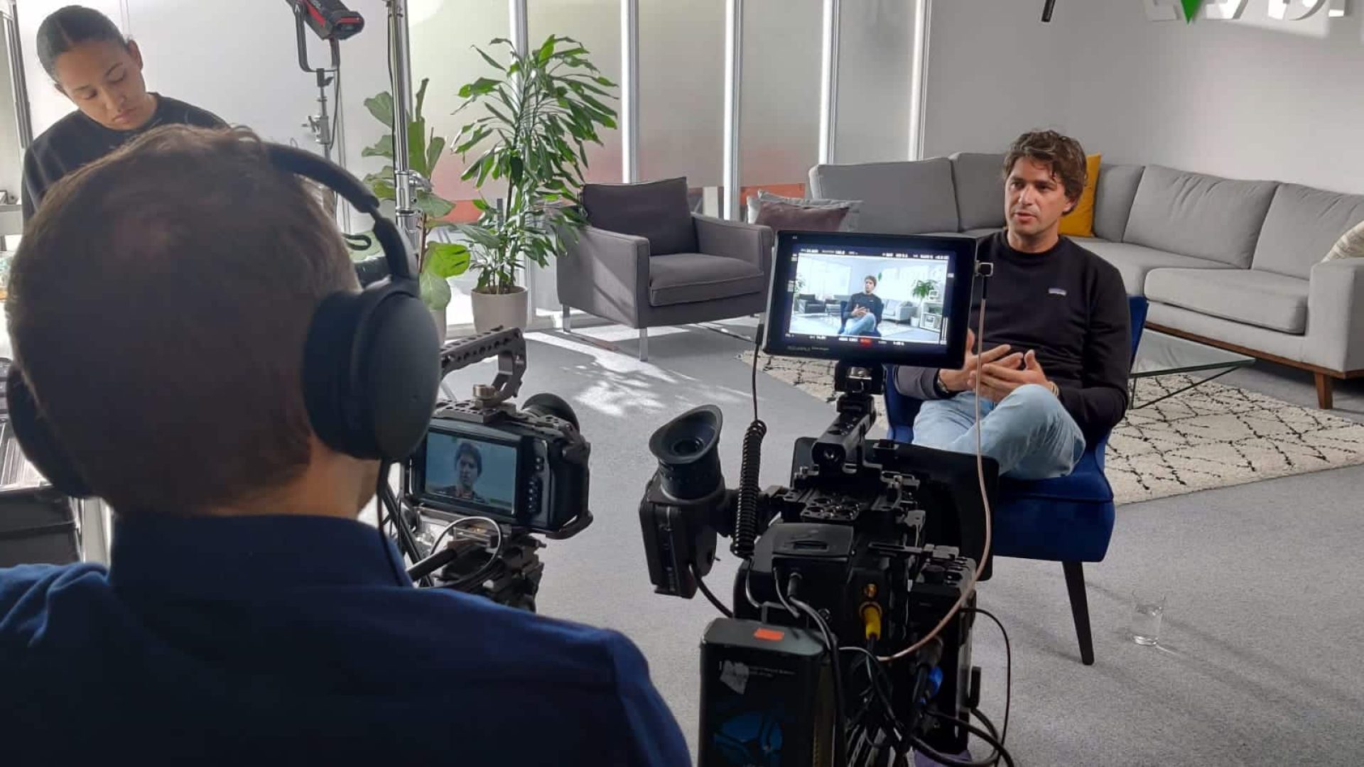 Filmmaker recording interview in modern office setting for video project.