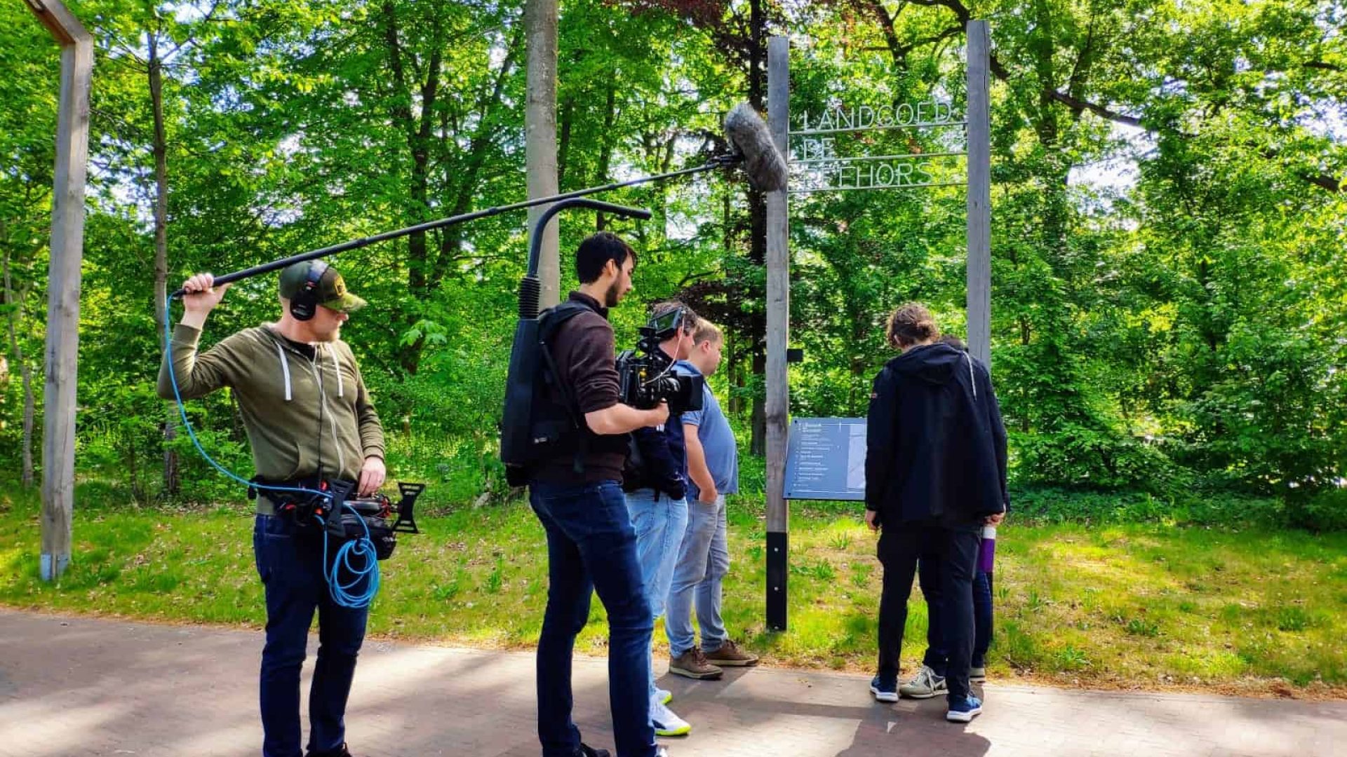 Creative team filming outdoors in a lush green park setting.