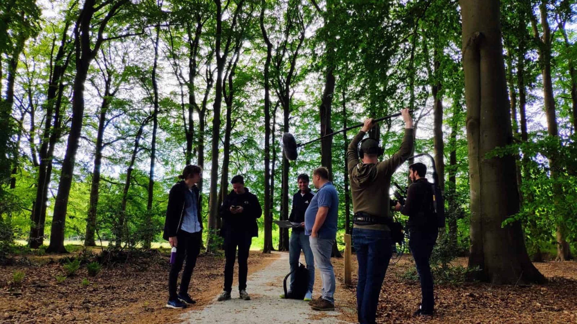 Group of videographers filming in a lush green forest setting.