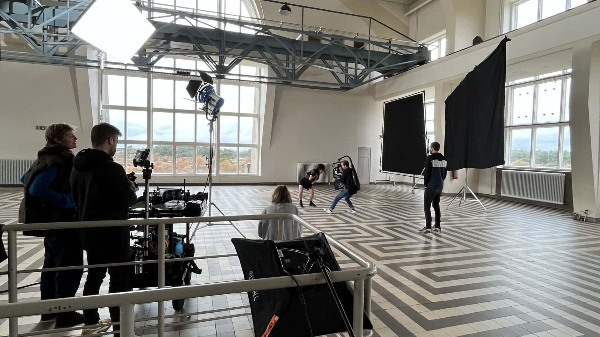 Interior of a film studio with crew filming a scene.