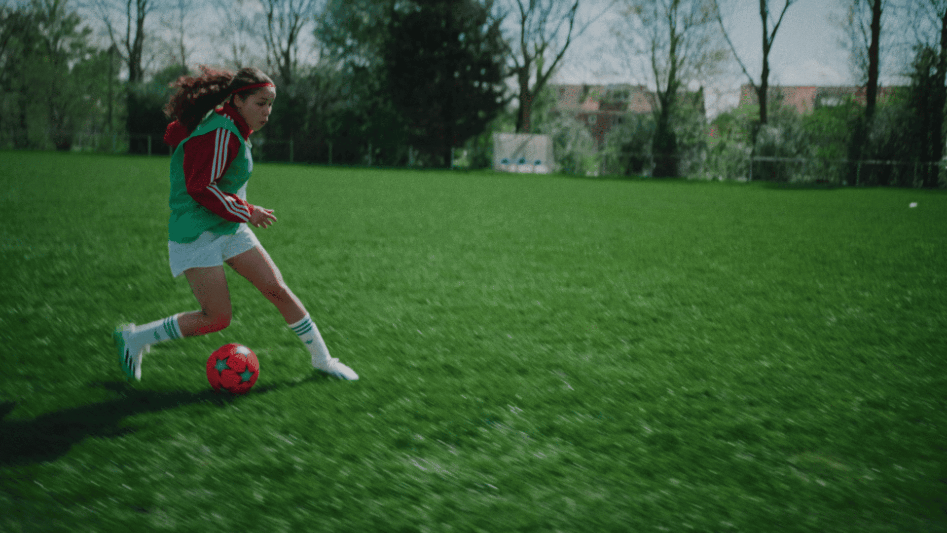 Young girl playing soccer on a green field for a video shoot.