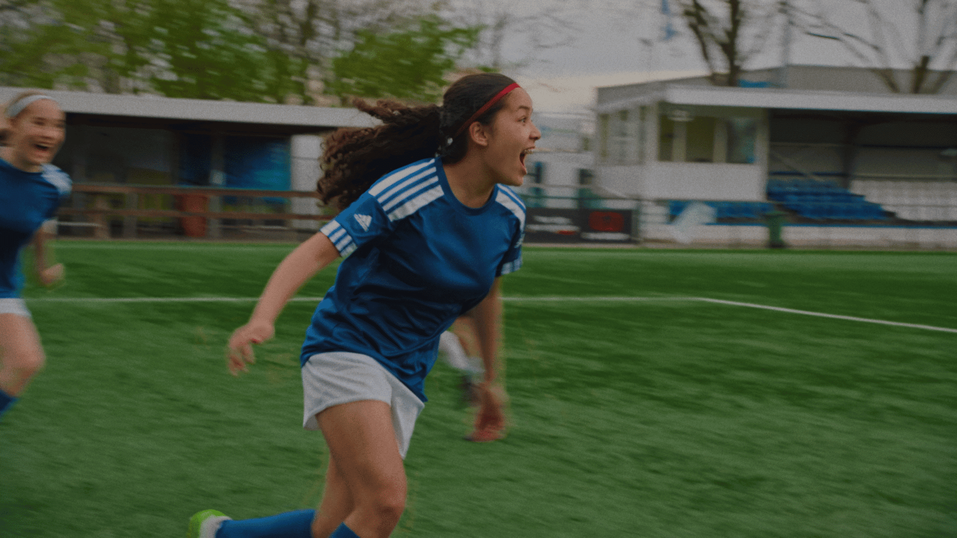 Young girl celebrating on a sports field during a game.