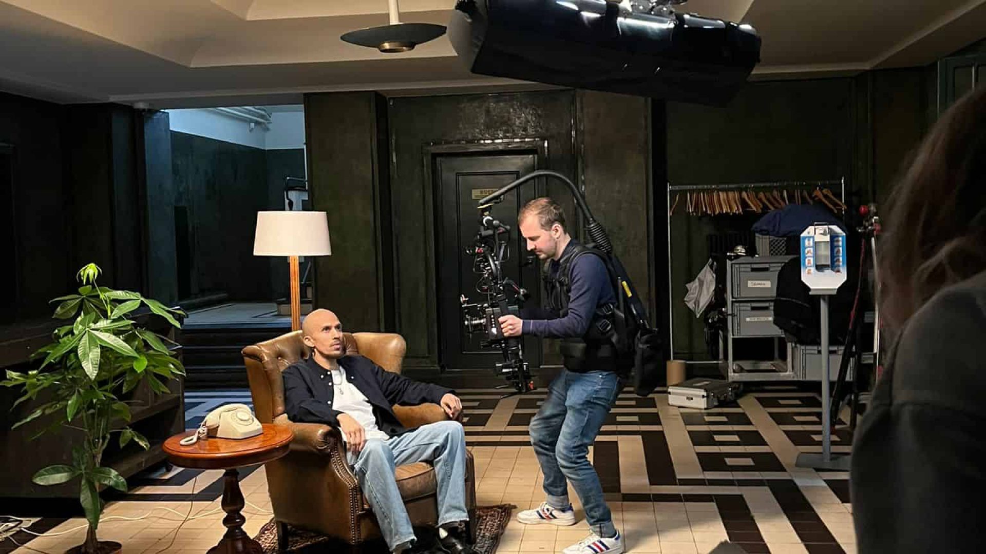 Professional video shoot capturing a seated interview with a camera operator and crew.