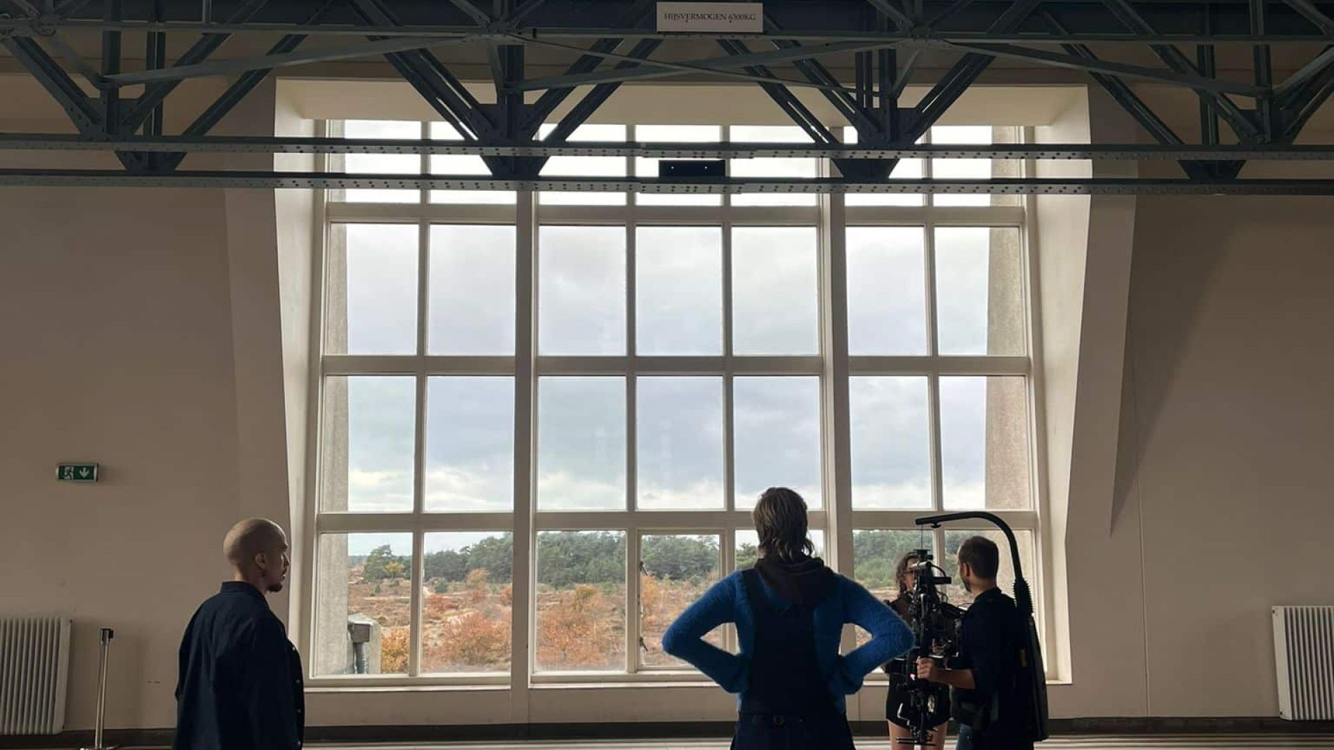 Bright spacious room with high ceiling, large window, and industrial design elements.