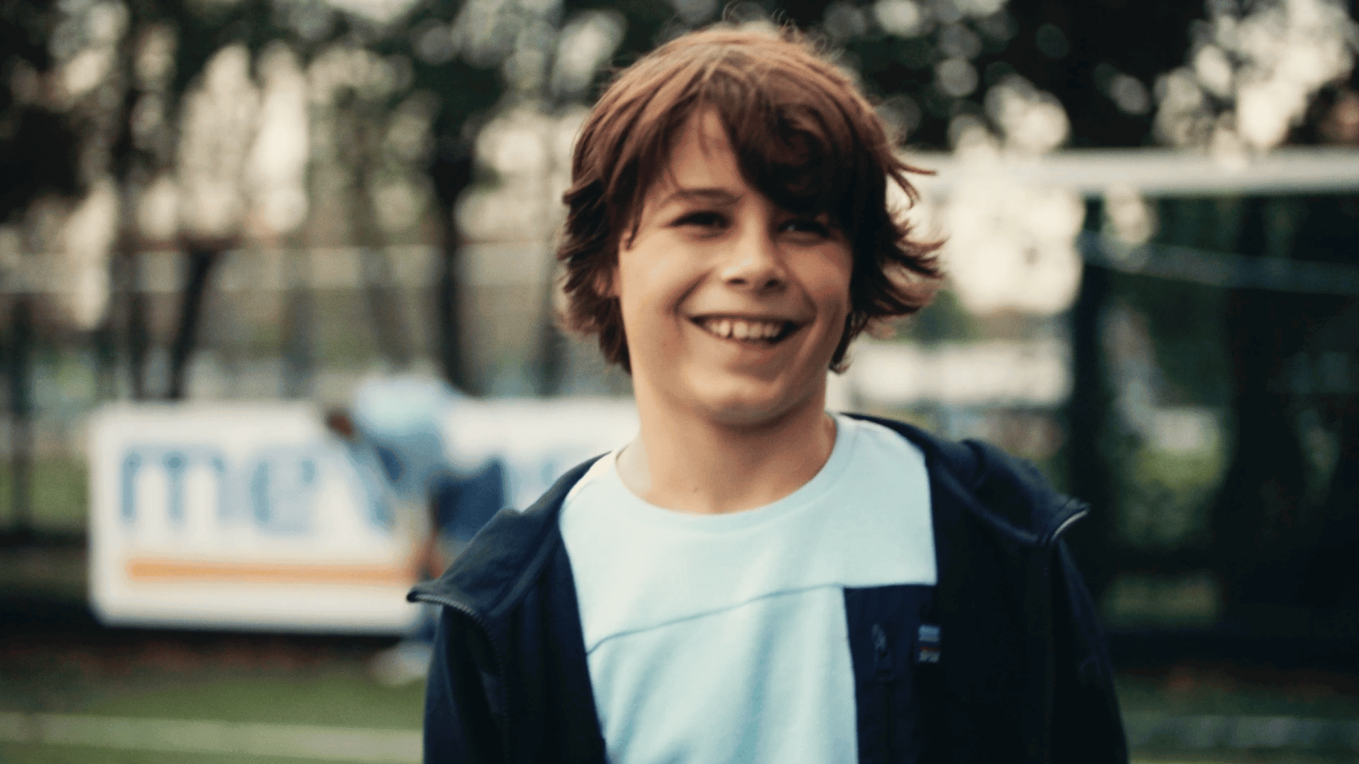 Young man smiling outdoors, representing creative video production services.