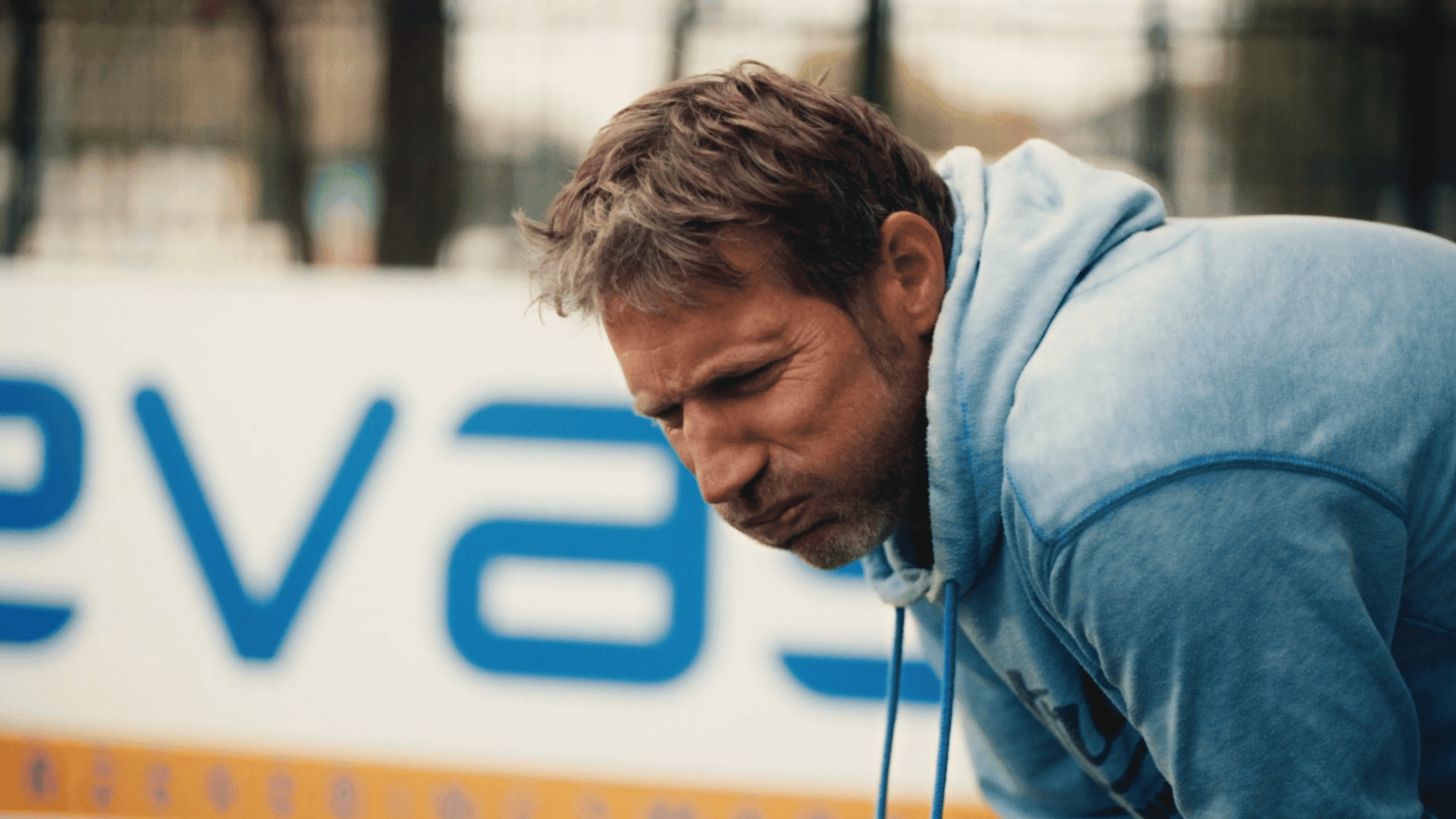 Man in blue hoodie working outdoors at Waves Video Agency.