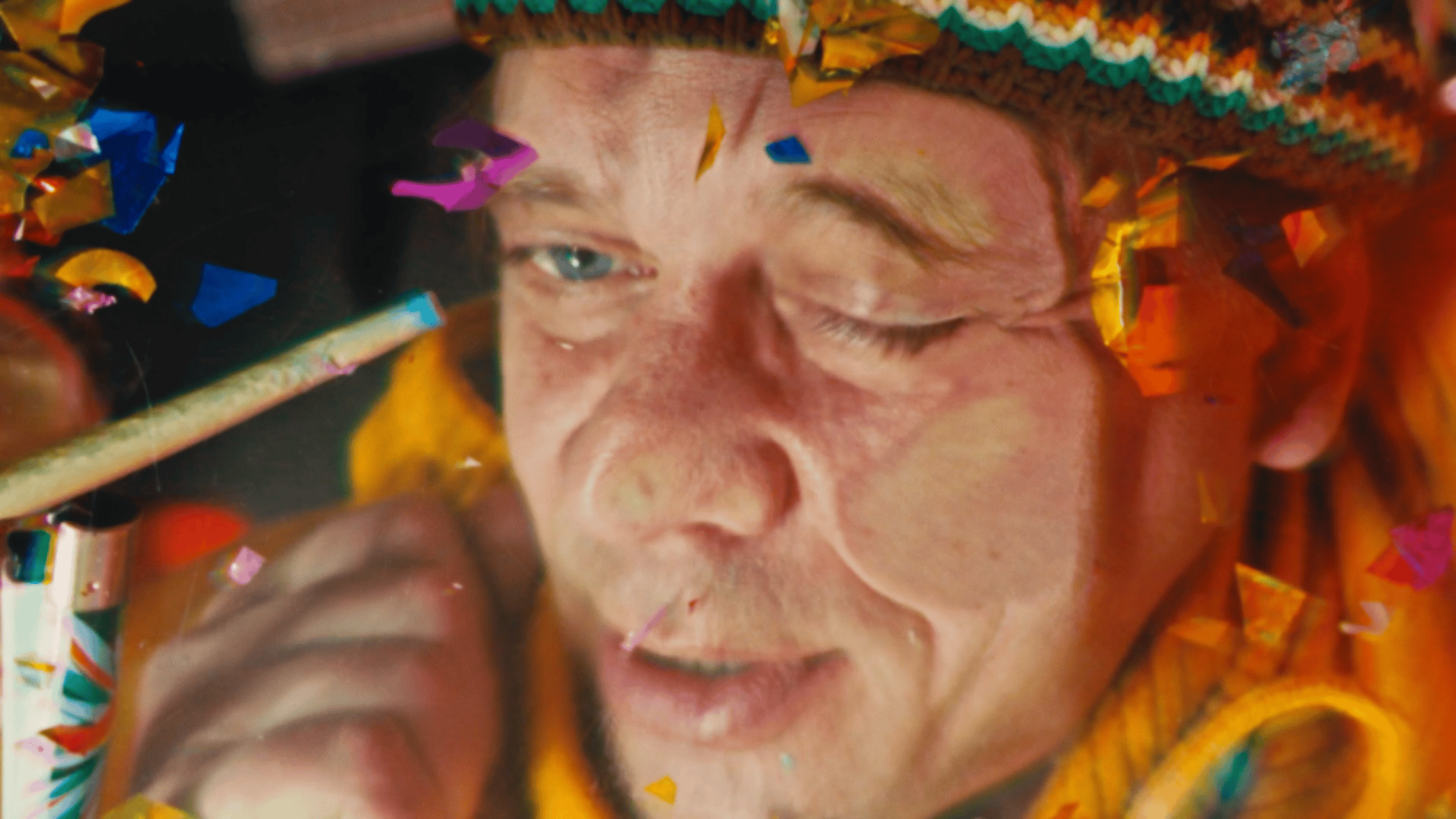 Woman celebrating with confetti, colorful party hat, and joyful expression.