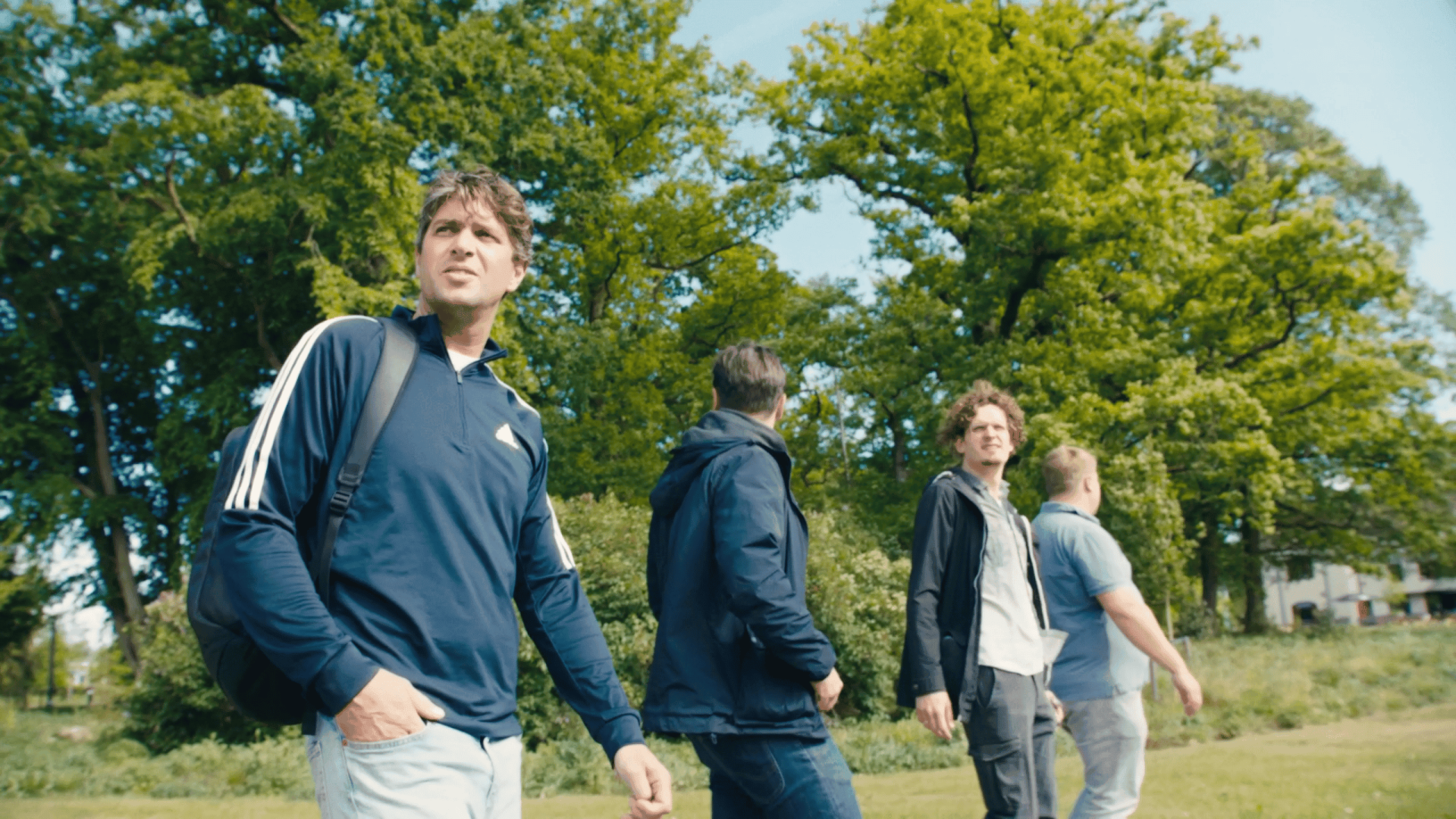 Group of young professionals walking outdoors in a park, discussing video projects.