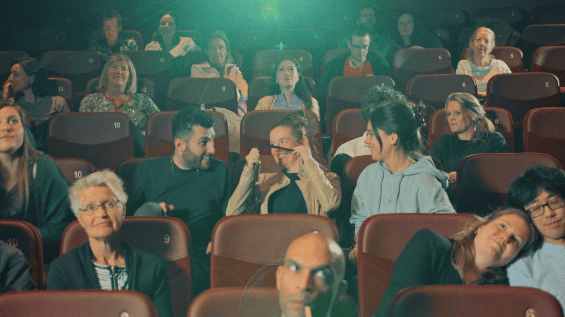 Audience watching a presentation in a theater setting, showcasing video production expertise.