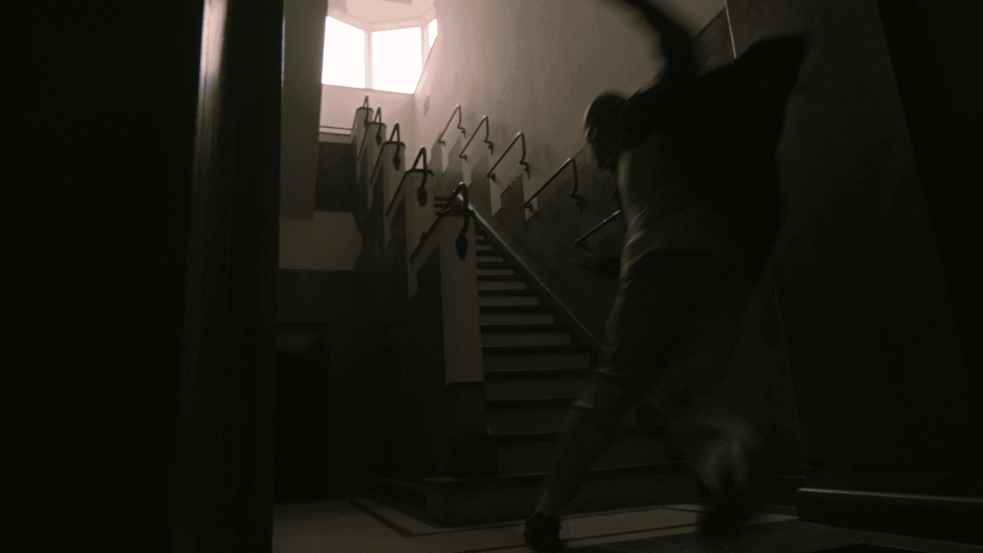 Person walking up a staircase in a dimly lit building interior.