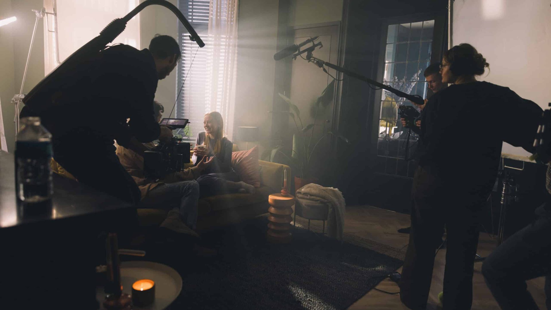 Set filming of a video shoot with crew and actress in a cozy, well-lit room.