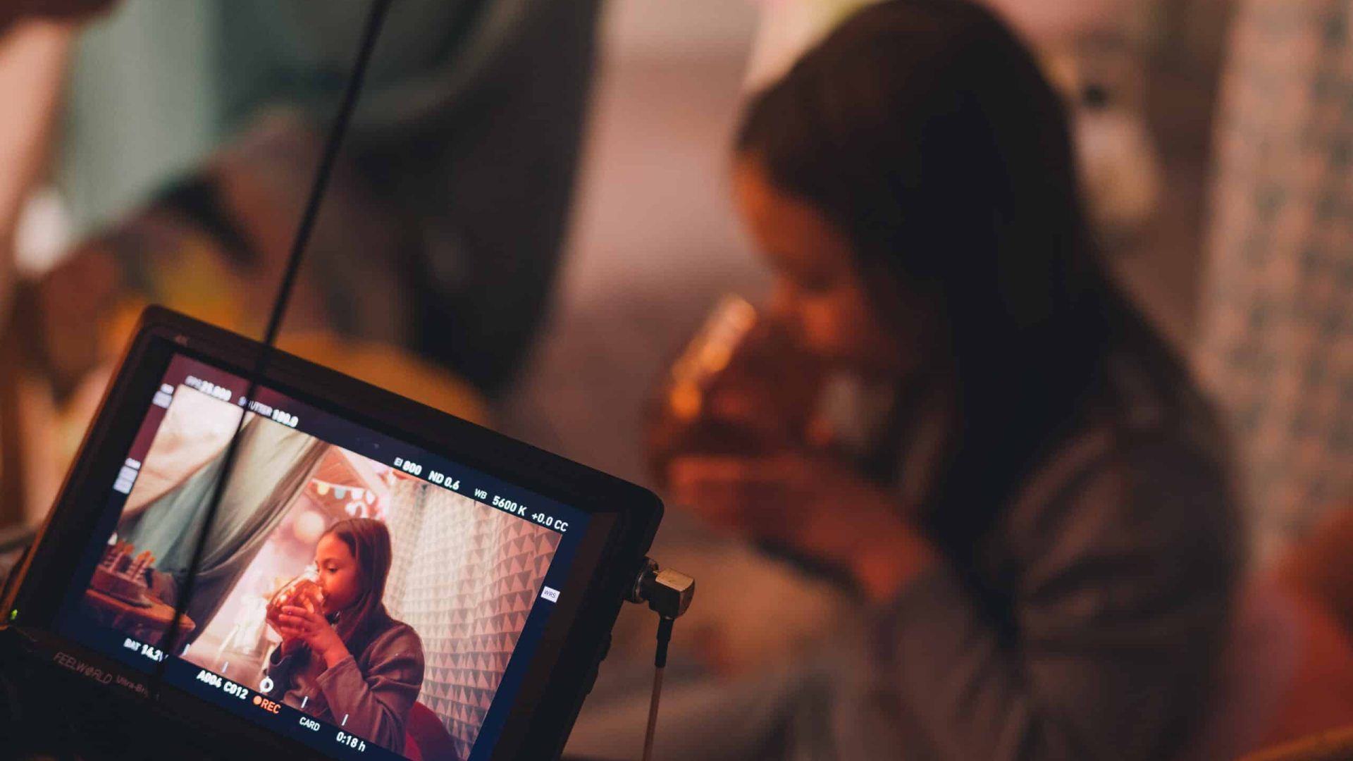 Creative video production team filming a woman in a cozy indoor setting.