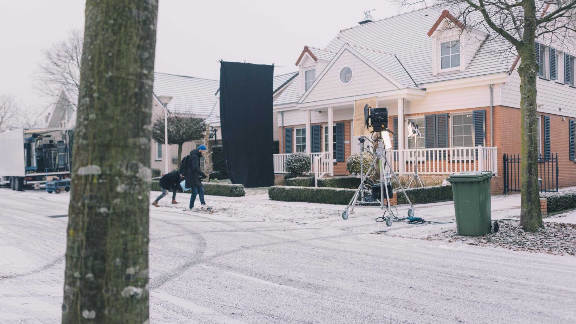 Outdoor film set in snowy neighborhood with camera equipment and crew.