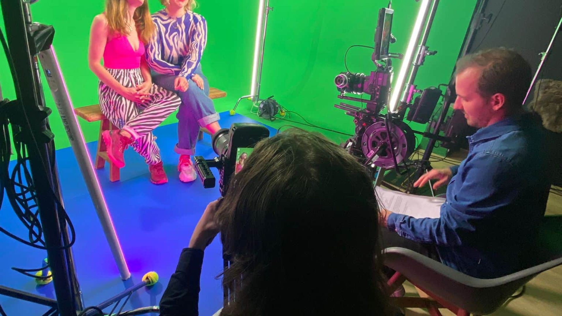 Green screen studio with crew filming two women for a creative video shoot.