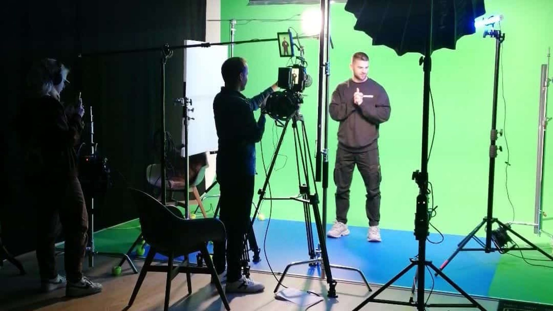 Professional video shoot with green screen and lighting setup in studio.