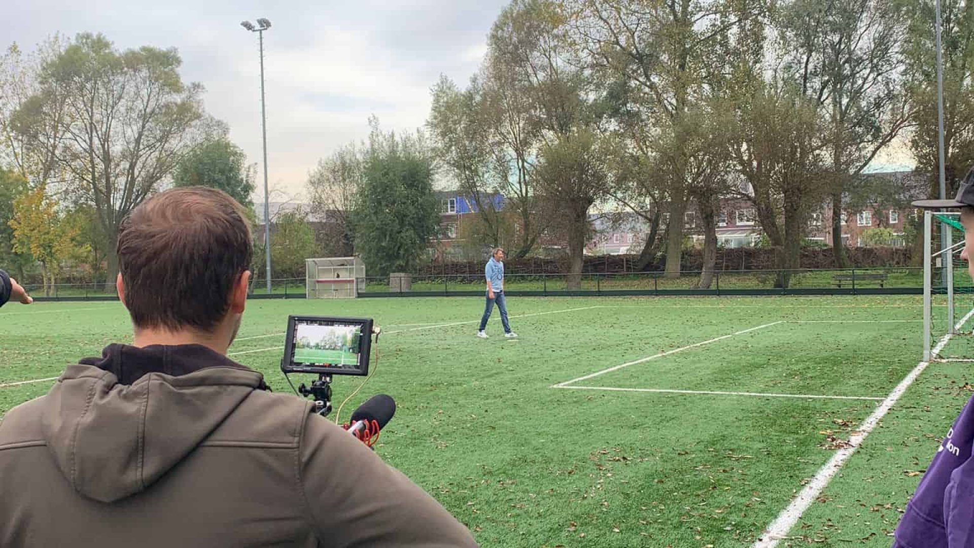 Video production outdoor sports field with camera operator filming athlete.